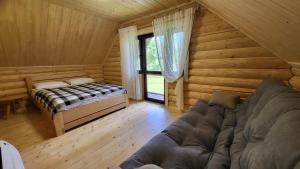 ミザヤリヤにあるКотеджі Карпати Festのログキャビン内のベッドとソファが備わる客室です。