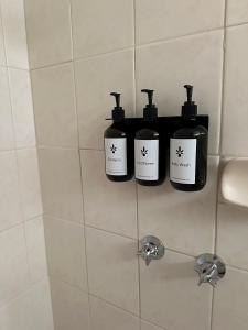 tre bottiglie di sapone su una mensola in bagno di Motel Bream a Mallacoota