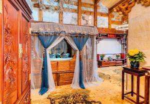 um quarto com uma cama com cortinas azuis num quarto em Lijiang Shuhe Zuo'an Inn em Lijiang