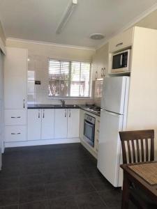a kitchen with white cabinets and a white refrigerator at Motel Bream in Mallacoota