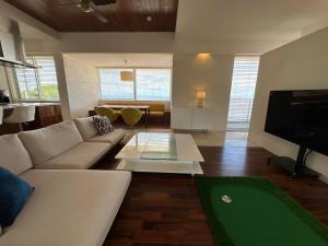 a living room with a couch and a flat screen tv at 海中道路を望むBBQ &ハンモック KATSUREN Blue in Uruma