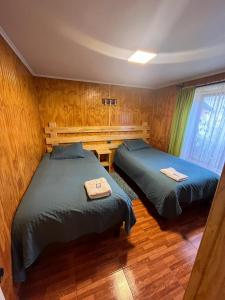 2 camas en una habitación con paredes de madera en Apart Hotel Español Coyhaique, en Coyhaique