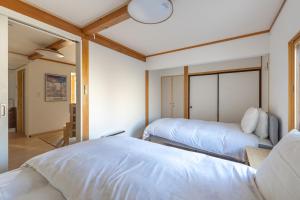 James House في نوزاوا أونسن: غرفة نوم بسريرين مع شراشف بيضاء