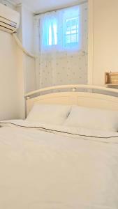un lit blanc dans une chambre avec une fenêtre dans l'établissement Gyeongbokgung Stay - Two Bedrooms, à Séoul