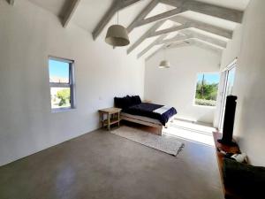 a white room with a bed and a couch and windows at Treasure in St Helena Bay