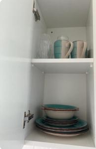 a white cabinet with cups and plates on plates at Cyprus Studio with pool near Beach in Peyia +22 photos