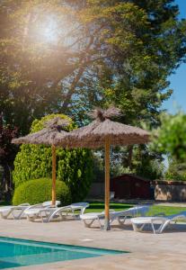 two umbrellas and lounge chairs next to a pool at La Botigueta de Bellmunt in Penellas