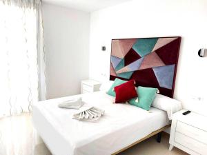 - une chambre avec un lit blanc et des oreillers colorés dans l'établissement Las Marinas 8o con Vistas al Mar y Piscina by Vero, à Benidorm