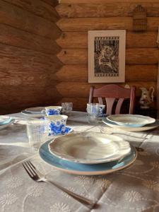 a table with plates and utensils on top of it at Tagavälja talu Cottage and Sauna on a farm B&B, rural experience in Atsalama