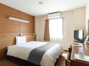 a hotel room with a bed and a desk and a television at Vessel Hotel Higashi Hiroshima in Higashihiroshima