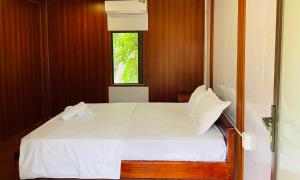 a bedroom with a white bed with a window at Huy-Mountainside Homestay in Phong Nha