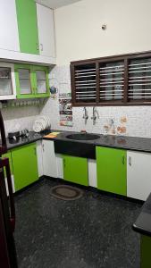 Bhoomiputra Mansion في ميسور: مطبخ مع دواليب خضراء وبيضاء ومغسلة