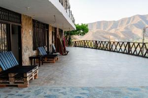 un balcone di un edificio con sedie e montagne sullo sfondo di Playa Alta Hostal a Santa Marta
