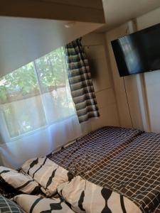 a bedroom with a bed in front of a window at Kék-Fehér Mobilház in Zsombó