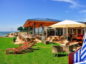 a restaurant with chairs and tables and umbrellas on the beach at On the top floor by the golf course in Fehmarn