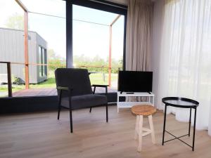 a living room with a chair and a television at Cottage in Menaam near Frisian Landscape in Menaldum