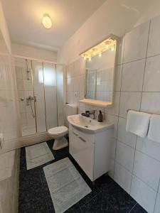 a white bathroom with a sink and a toilet at Apartments & Rooms Samohod in Vodice