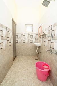 - Baño con cubo rosa y lavamanos en Hotel Amman Residency, en Rameswaram