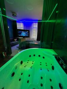 a green tub in a room with a tv at Gold Glass Jacuzzi Sauna Rynek-Parking in Kielce