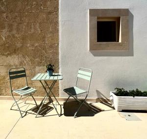 zwei Stühle und ein Tisch vor einer Wand in der Unterkunft Masseria Spiga in Gravina in Puglia