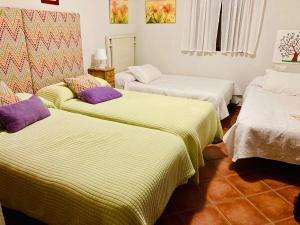 Habitación con 3 camas con sábanas verdes y blancas en Alojamiento rural Rancho Valero en El Bosque