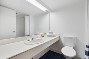 uma casa de banho branca com um lavatório e um WC em Glenelg Dockside Motel em Adelaide