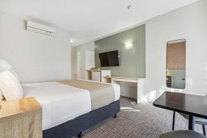 Habitación de hotel con cama y escritorio en Glenelg Dockside Motel en Adelaida