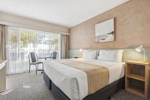 a hotel room with a large bed and a desk at Glenelg Dockside Motel in Adelaide