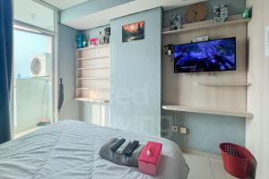 ein Schlafzimmer mit einem Bett und einem Fernseher an der Wand in der Unterkunft RedLiving Apartemen Treepark City - Nuansa Property Tower Alpine in Kebonnanas + 20 Fotos