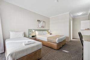 Habitación de hotel con 2 camas y mesa en Glenelg Dockside Motel en Adelaida