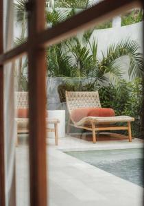 two wicker chairs sitting on a patio with plants at Villa Alya Seaside by Pura Homes in Canggu +29 photos