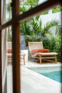 a patio with two chairs and a swimming pool at Villa Alya Seaside by Pura Homes in Canggu