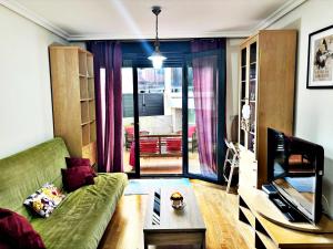 ein Wohnzimmer mit einem grünen Sofa und einem TV in der Unterkunft Holibai, Parruliña, Estudio Con Terraza, Piscina, Parking Wifi in Baiona