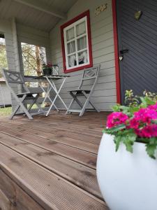 a porch with chairs and a table and flowers at Metsatuule puhkeküla in Hiiumaa
