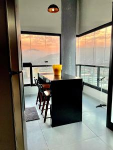 uma cozinha com mesa e cadeiras num quarto com janelas em APARTAMENTO NOVO A 600 Metros da PRAIA no Guarujá