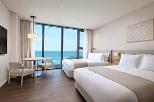 Postel nebo postele na pokoji v ubytování Shilla Stay Plus Iho Tewoo Ocean Front