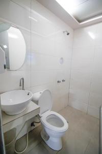 a white bathroom with a toilet and a sink at Astrotel Avenida in Manila