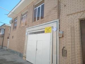 a white garage door on a brick building at Suzangaran House in Samarkand