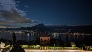 a building on the shore of a lake at night at Hotel Diana in San Zeno di Montagna