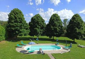 a pool in a field with chairs and an umbrella at La Casatorre Di Ponticello in Filattiera