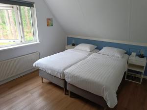 um quarto com uma grande cama branca e uma janela em Bosvilla Lochem em Lochem