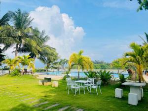 einen Tisch und Stühle im Gras neben einem Pool in der Unterkunft Bay Beach Hotel in Nilaveli