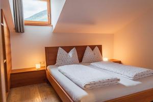 Schlafzimmer mit einem Bett mit weißer Bettwäsche und einem Fenster in der Unterkunft Huberhof in Natz-Schabs