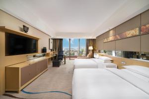 um quarto de hotel com 4 camas e uma televisão de ecrã plano em Dongguan Royal Garden Hotel em Dongguan