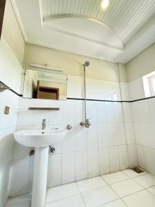 a white bathroom with a sink and a mirror at Atlas Gold Hotel in Islamabad