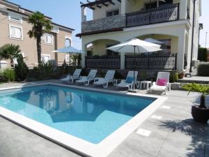 una piscina con sillas y una sombrilla junto a un edificio en Villa Luka Apartent Gray, en Funtana