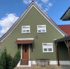 une maison verte avec un banc devant elle dans l'établissement Haus62, à Weißwasser
