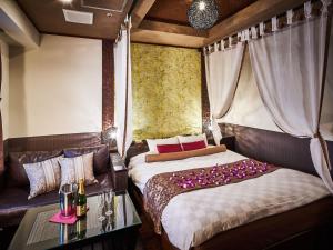 ein Schlafzimmer mit einem Bett, einem Sofa und einem Tisch in der Unterkunft BaliAn Resort Chiba-Chuo in Chiba