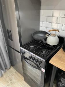a kitchen with a stove with a tea pot on it at PINE COTTAGE Self catering fully equipped 2 bedroom, Queen bed 3 singles 65sqm cosy private cottage in Durban