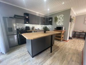 a kitchen with black cabinets and a wooden counter top at PINE COTTAGE Self catering fully equipped 2 bedroom, Queen bed 3 singles 65sqm cosy private cottage in Durban